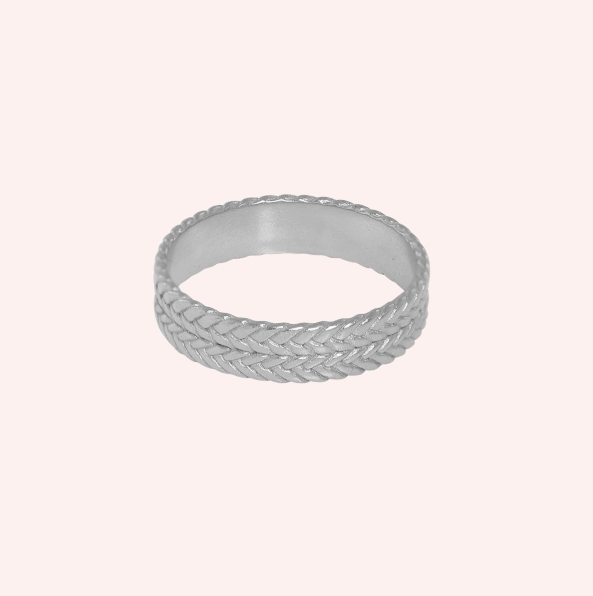 Band_ring_in_sterling_silver_with_braided_design_at_front_angle_on_solid_pink_background