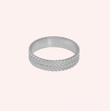Band_ring_in_sterling_silver_with_braided_design_at_front_angle_on_solid_pink_background
