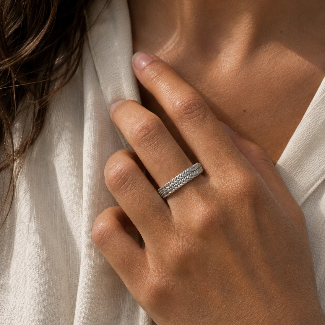 Band_ring_in_gold_plated_silver_with_braided_design_at_angle_view_on_soft_fabric_background