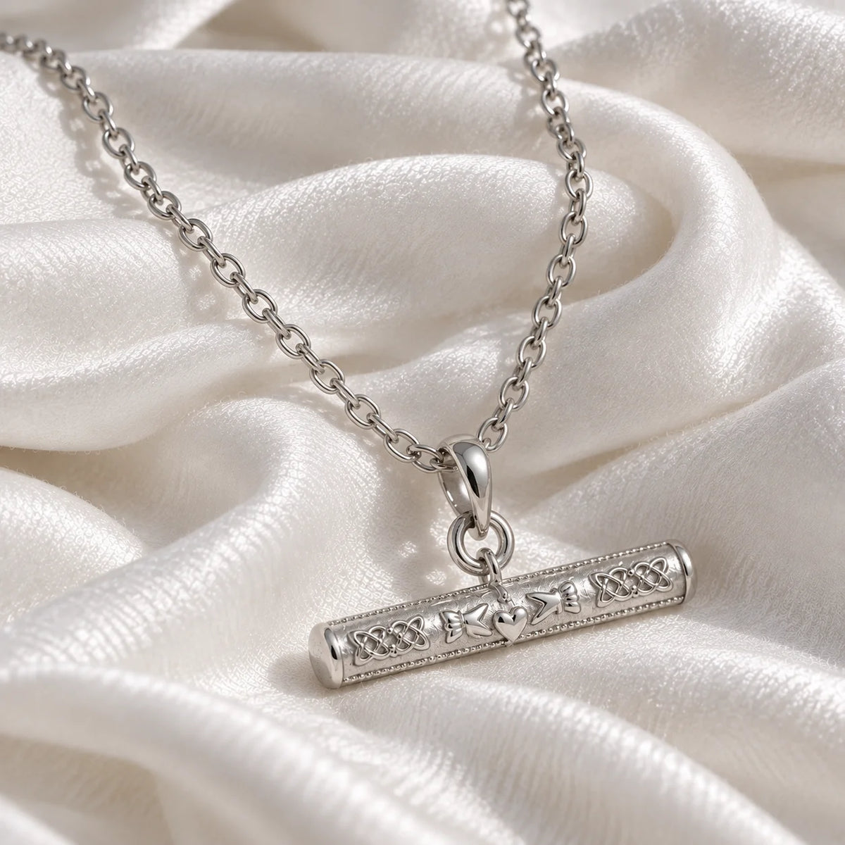 Bar_necklace_in_sterling_silver_with_claddagh_design_at_slight_angle_view_on_soft_fabric_background