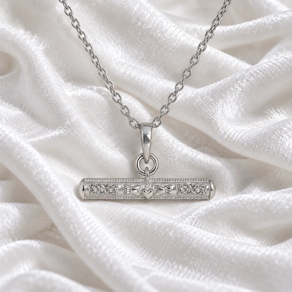 Bar_necklace_in_sterling_silver_with_claddagh_design_at_front_angle_view_on_soft_fabric_background