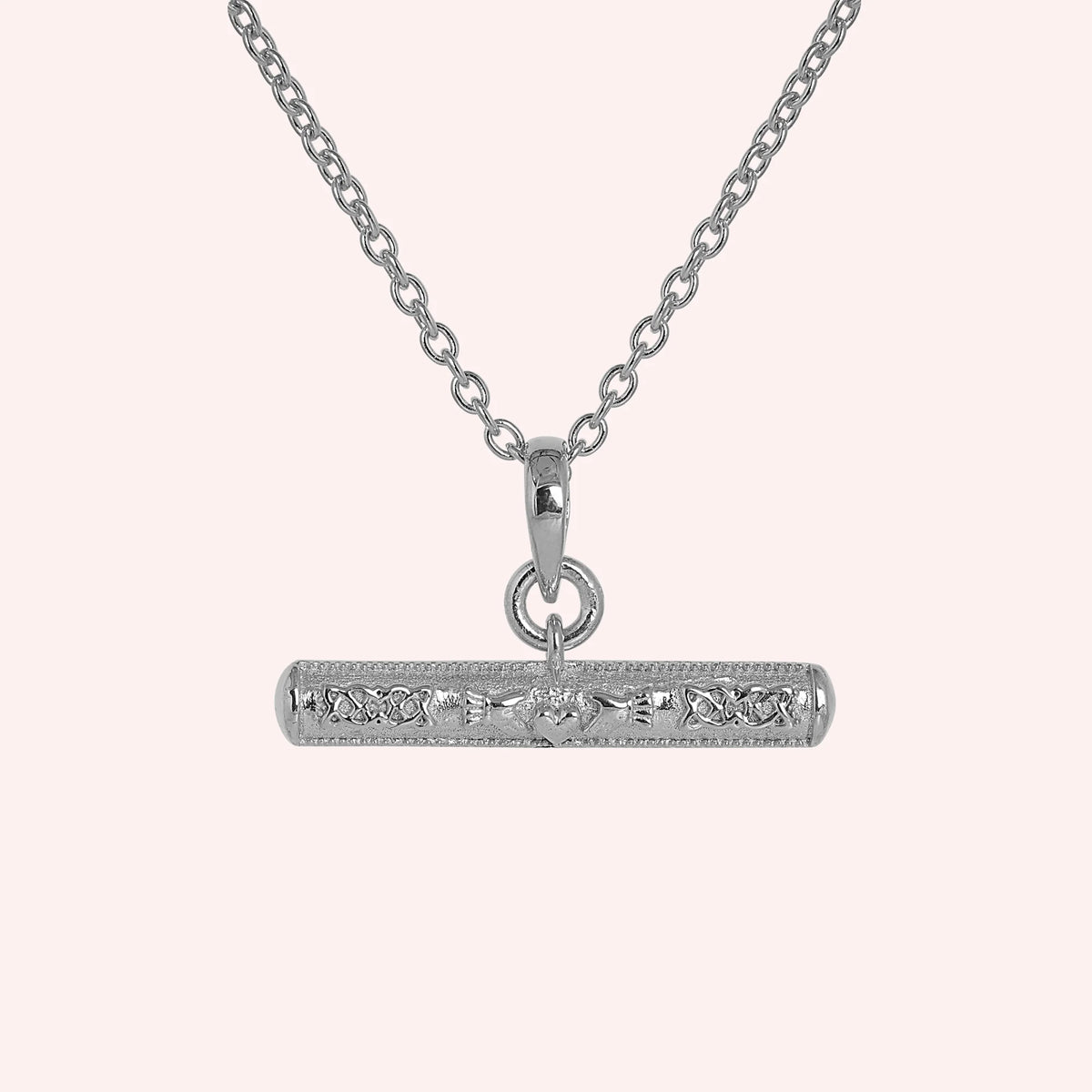 Bar_necklace_in_sterling_silver_with_claddagh_design_at_front_angle_view_on_solid_pink_background