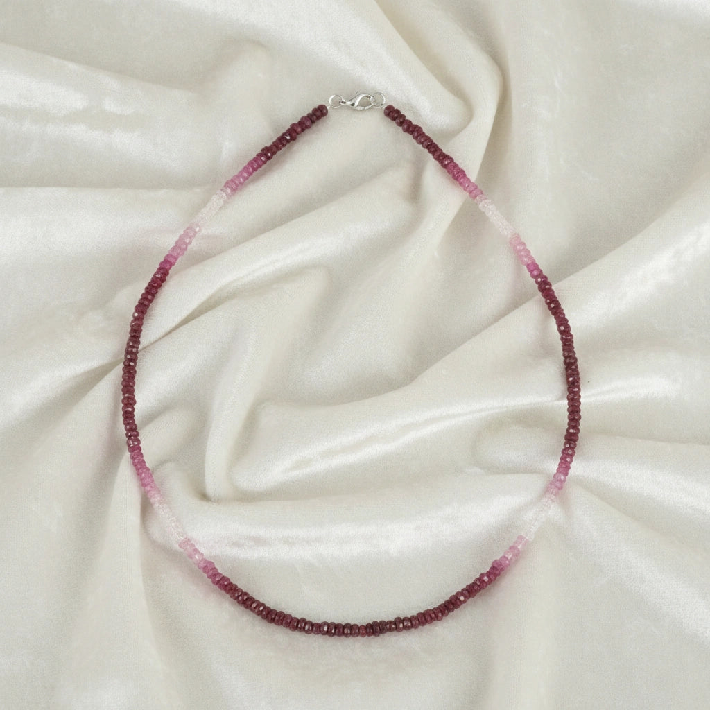 Beaded_necklace_in_ombre_effect_with_ruby_stones_in_gradient_design_in_front_angle_on_a_white_fabric_background