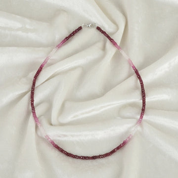 Beaded_necklace_in_ombre_effect_with_ruby_stones_in_gradient_design_in_front_angle_on_a_white_fabric_background