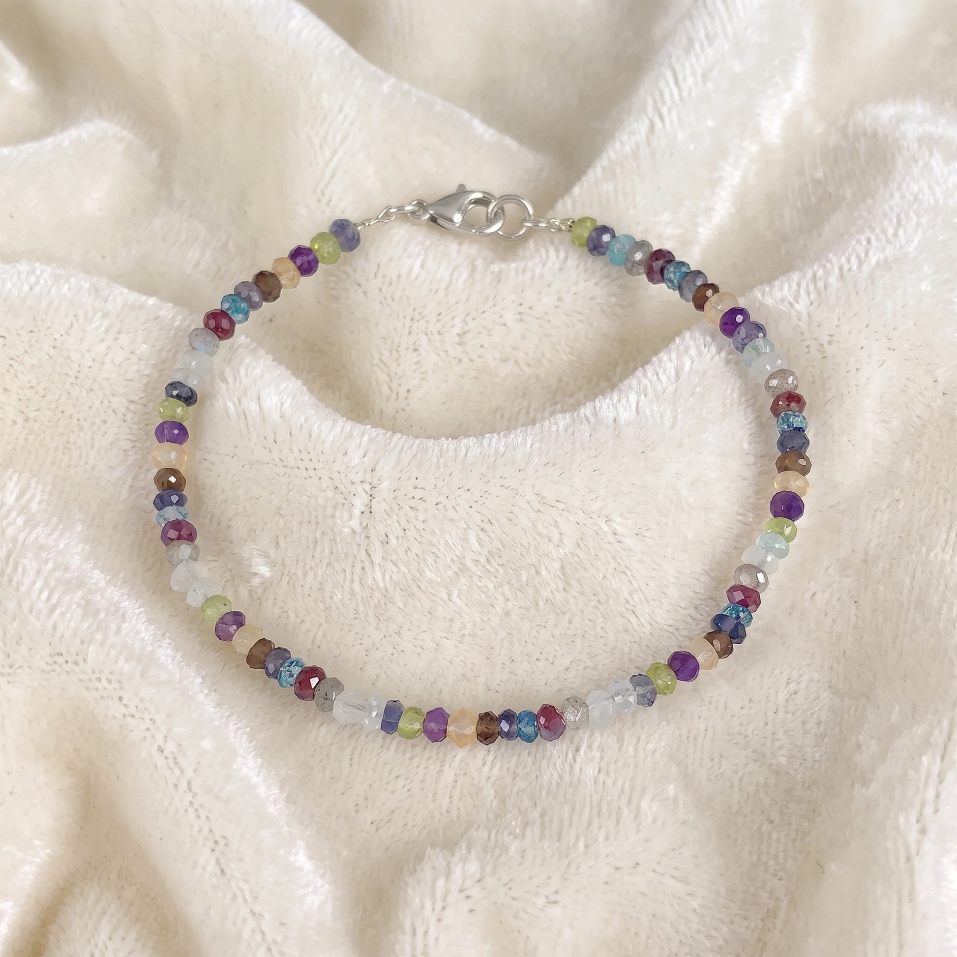 Beads_bracelet_with_multi_stones_in_sterling_silver_at_front_angle_view_on_soft_fabric_background