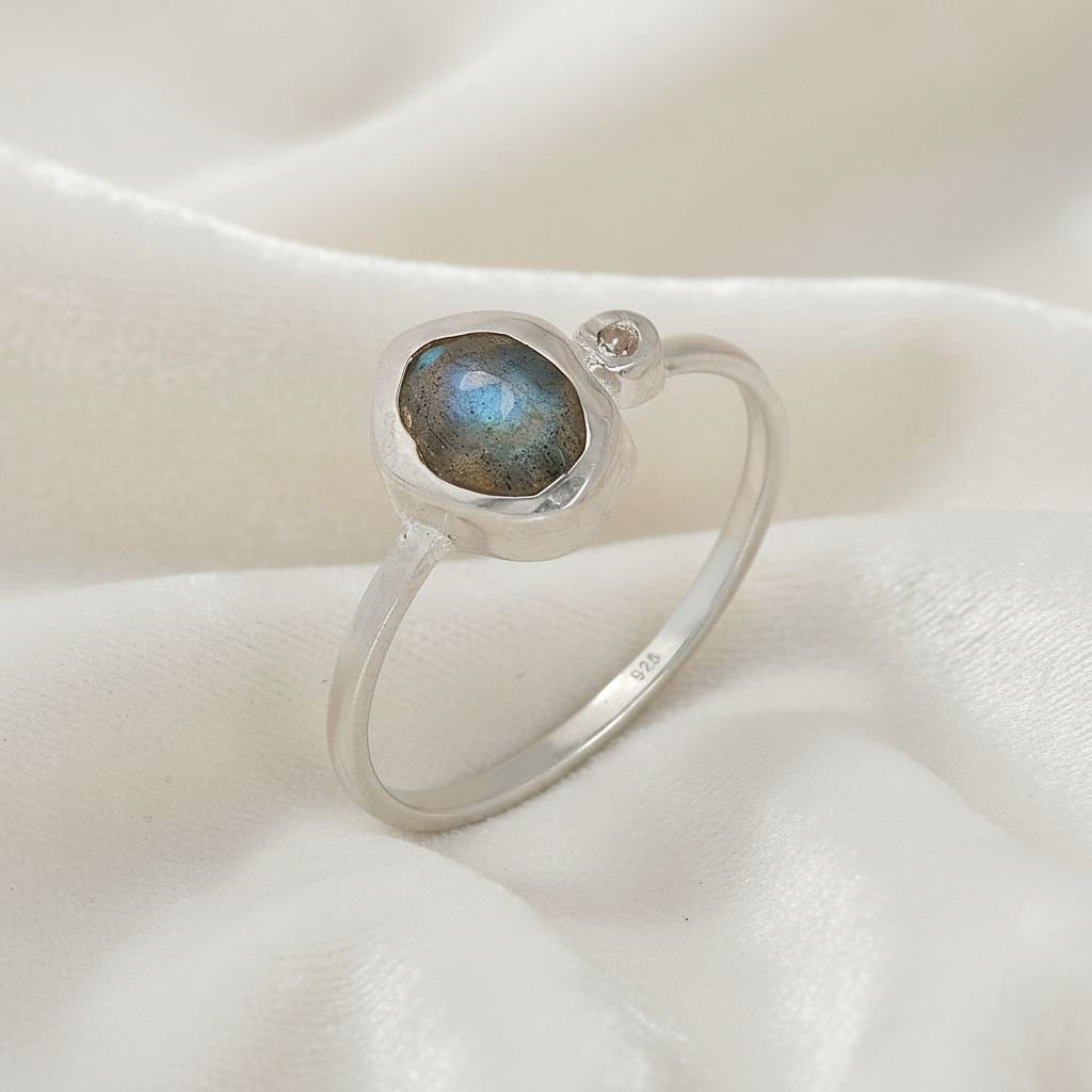 Bezel-set-ring-with-labradorite-and-white-topaz-stones-sterling-silver-angled-view-on-satin-background