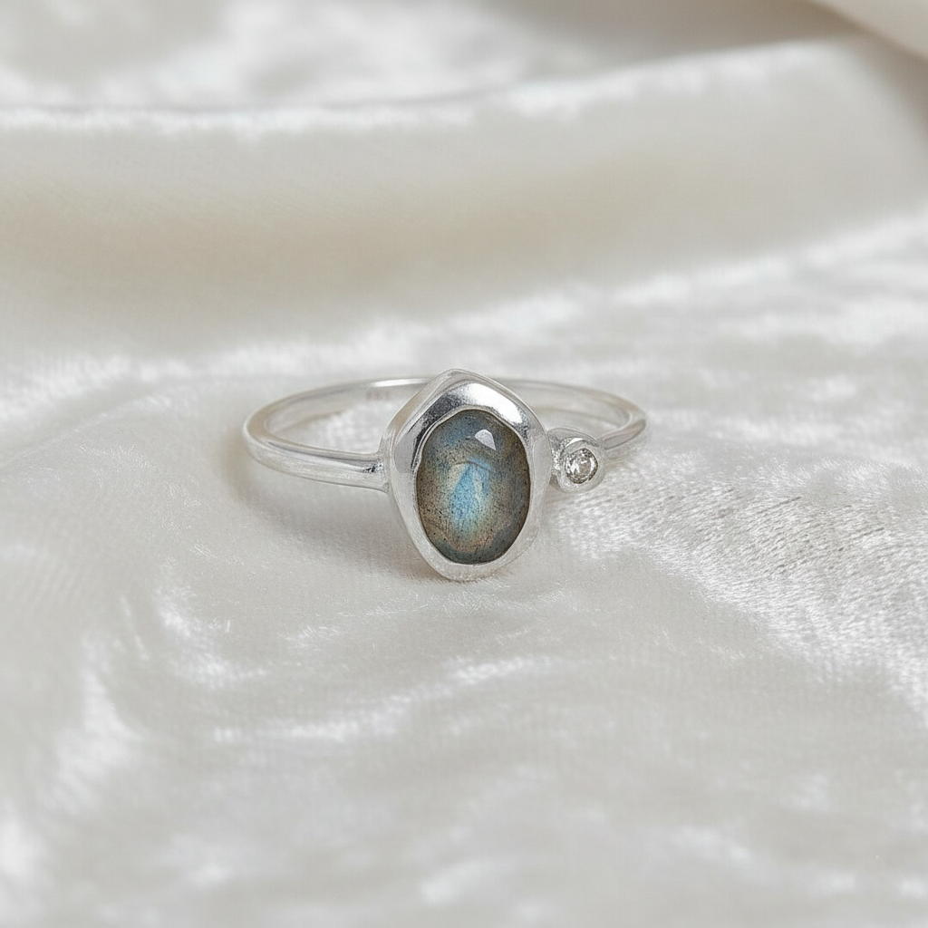 Bezel-set-ring-with-labradorite-and-white-topaz-stones-sterling-silver-front-view-on-satin-background