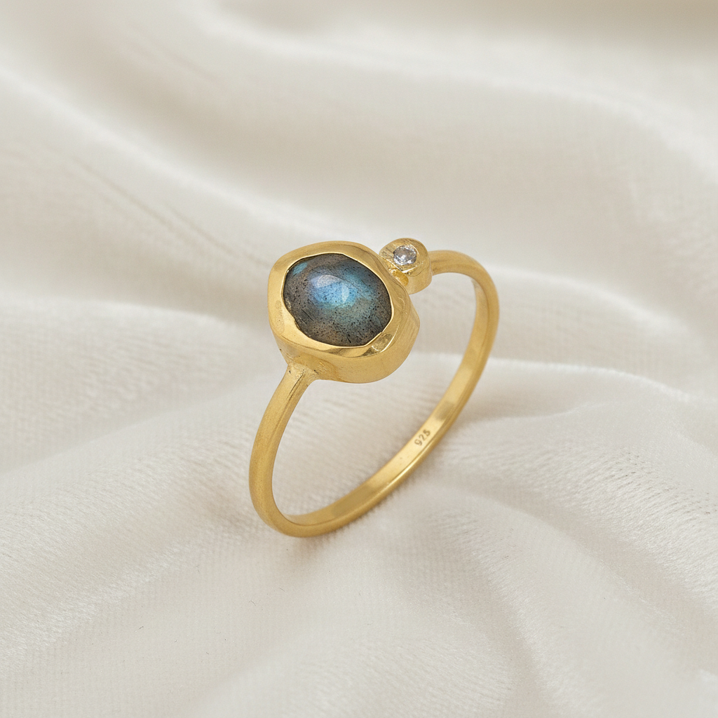 Bezel-set-ring-with-labradorite-and-white-topaz-stones-gold-plated-silver-angled-view-on-satin-background