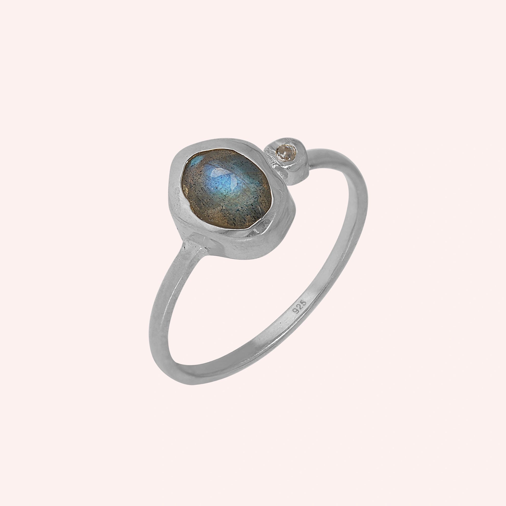 Bezel-set-ring-with-labradorite-and-white-topaz-stones-sterling-silver-angled-view-on-soft-pink-background