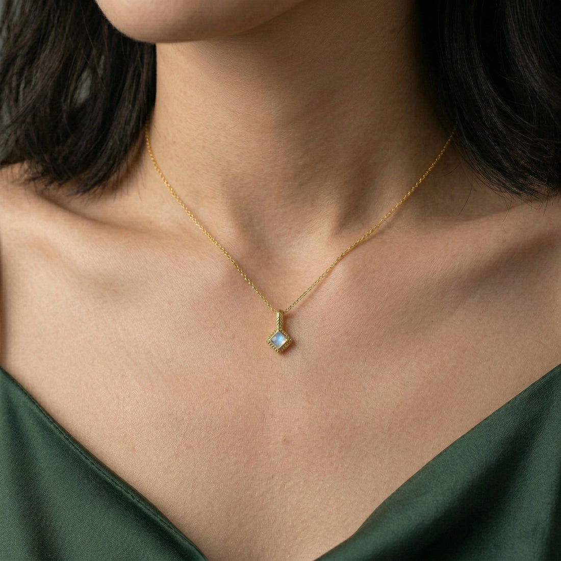 Birthstone_necklace_in_gold_plated_silver_with_square_cut_moonstone_pendant_in_slighlty_angled_view_on_soft_white_fabric_background