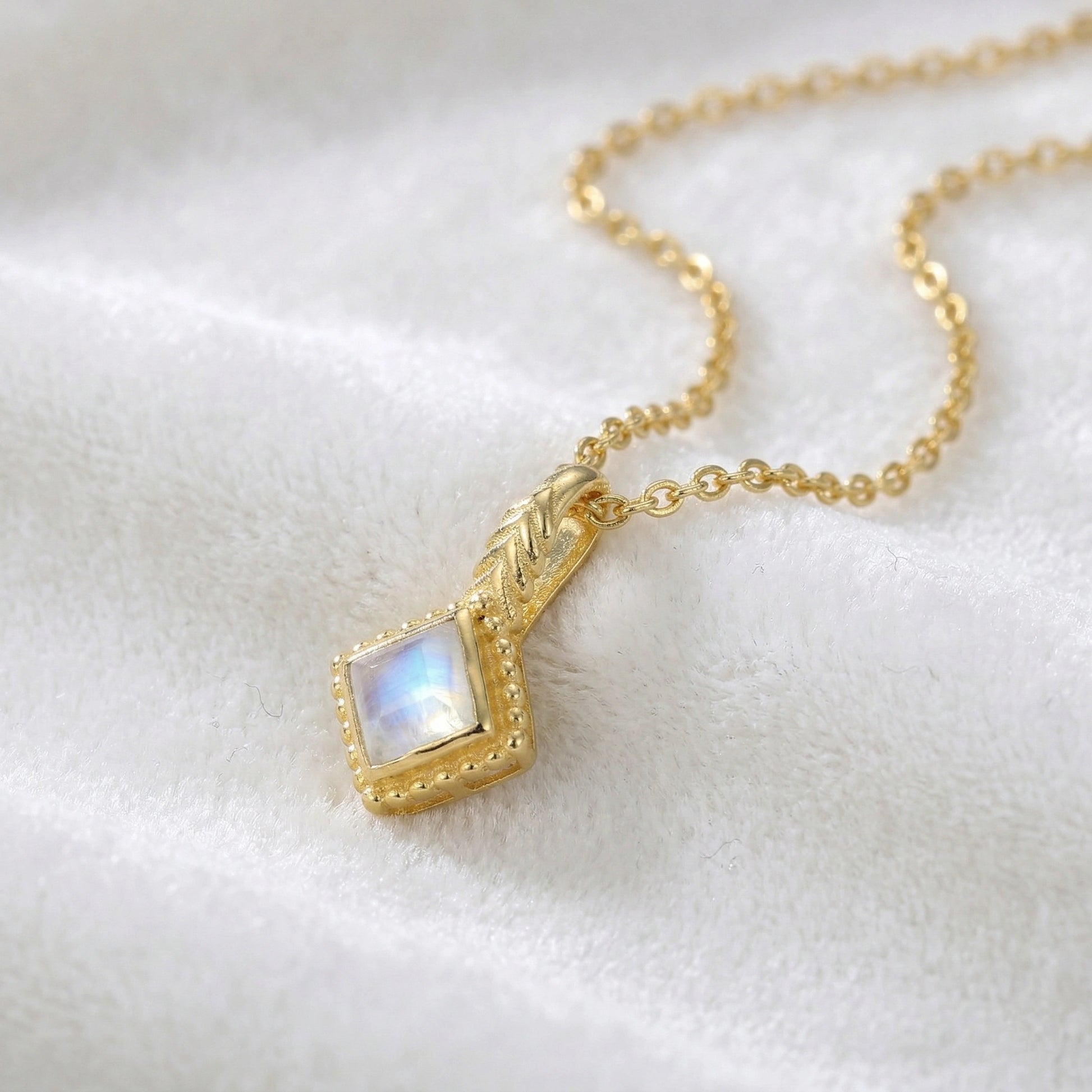 Birthstone_necklace_in_gold_plated_silver_with_square_cut_moonstone_pendant_in_slighlty_angled_view_on_soft_white_fabric_background