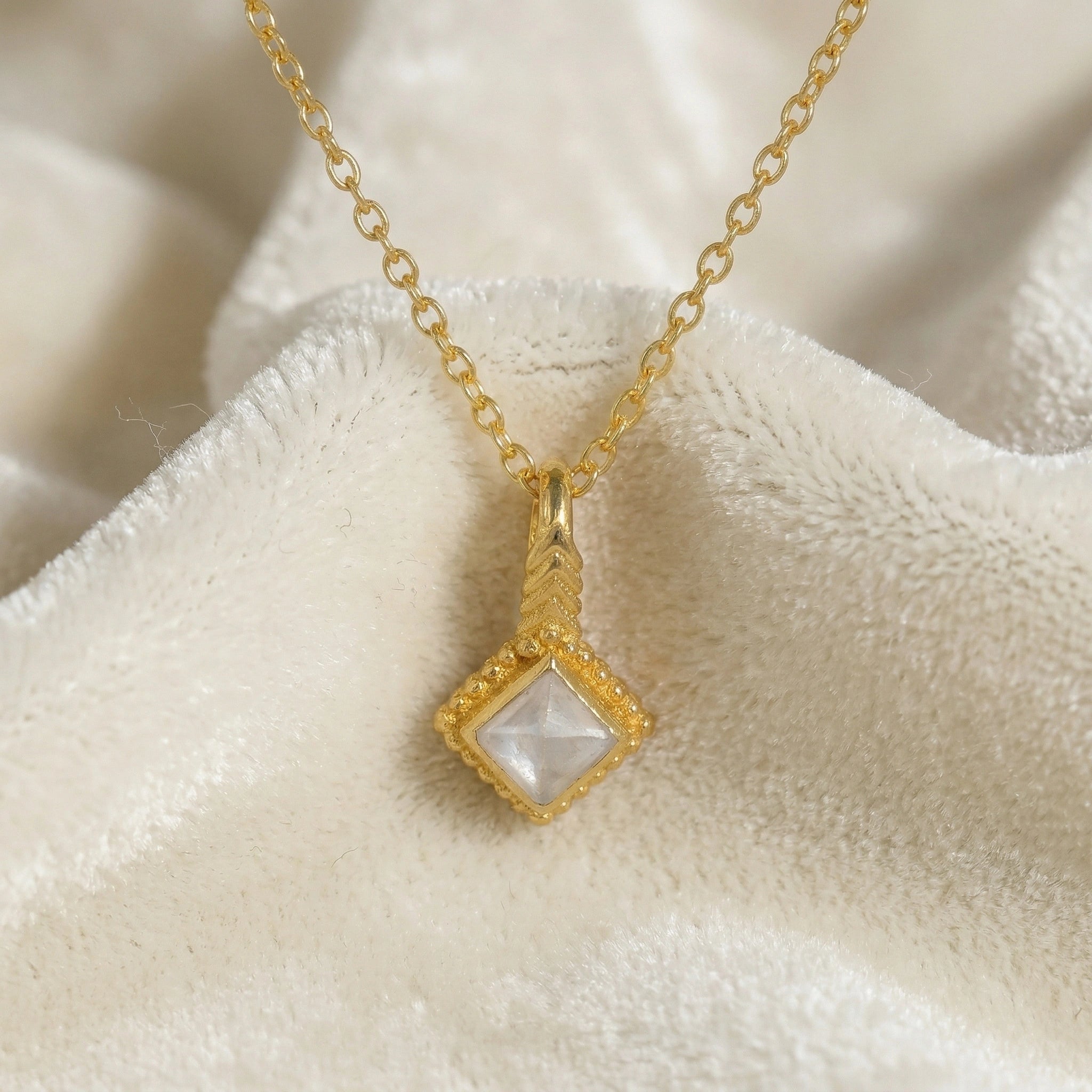Birthstone_necklace_in_gold_plated_silver_with_square_cut_moonstone_pendant_in_front_angle_view_on_soft_white_fabric_background