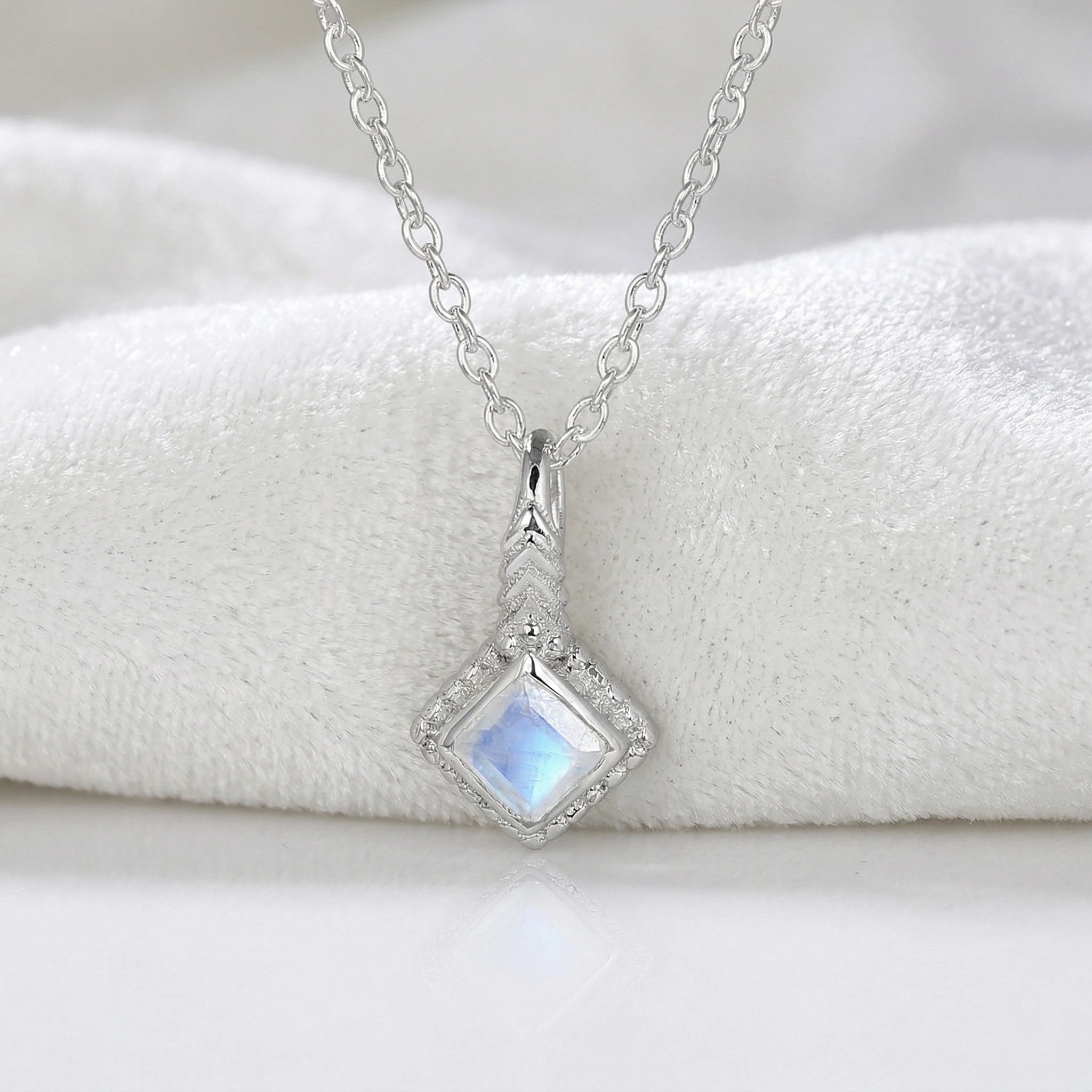 Birthstone_necklace_in_sterling_silver_with_square_cut_moonstone_pendant_in_front_angle_view_on_soft_white_fabric_background