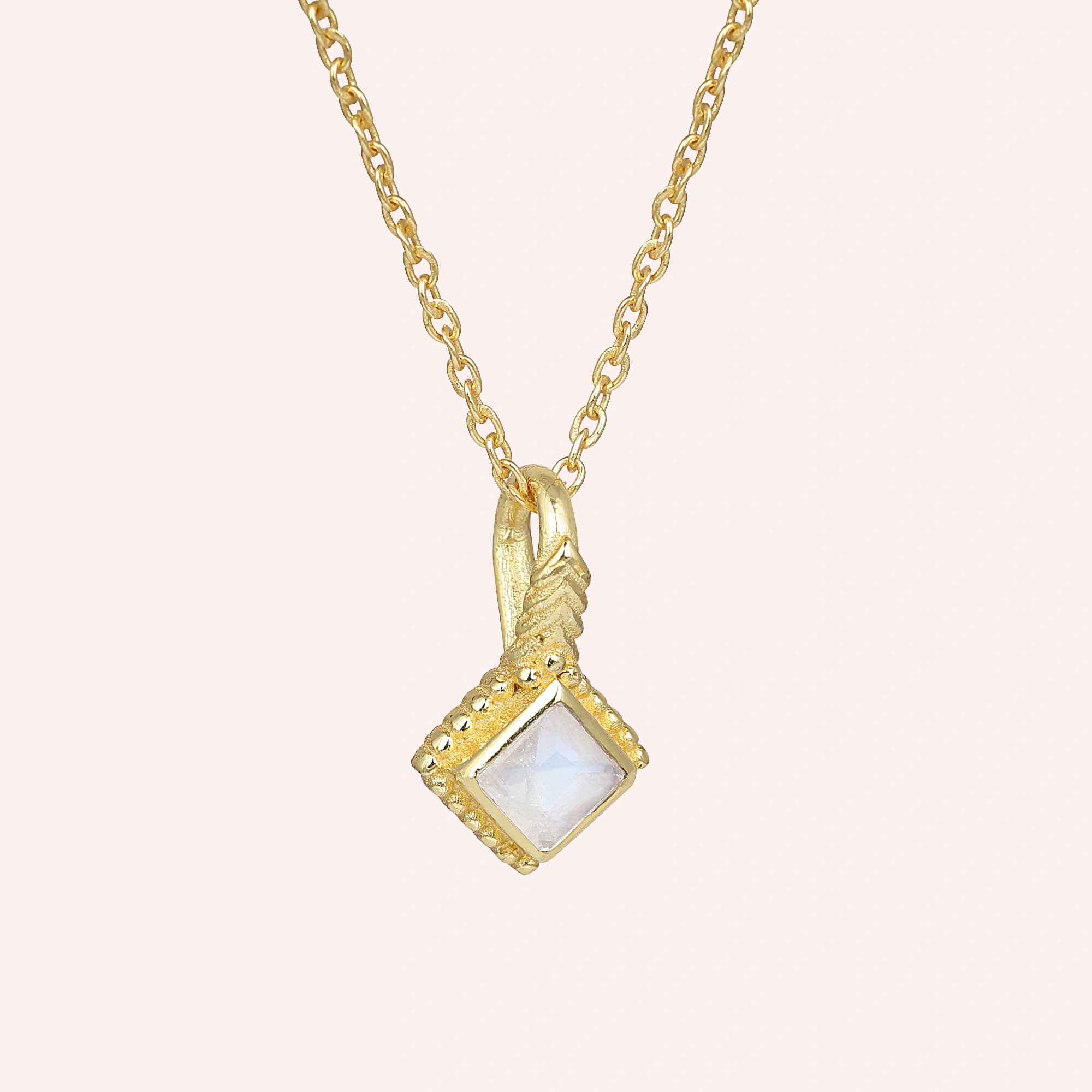 Birthstone_necklace_in_gold_plated_silver_with_square_cut_moonstone_pendant_in_slightly_angled_view_on_solid_pink_background