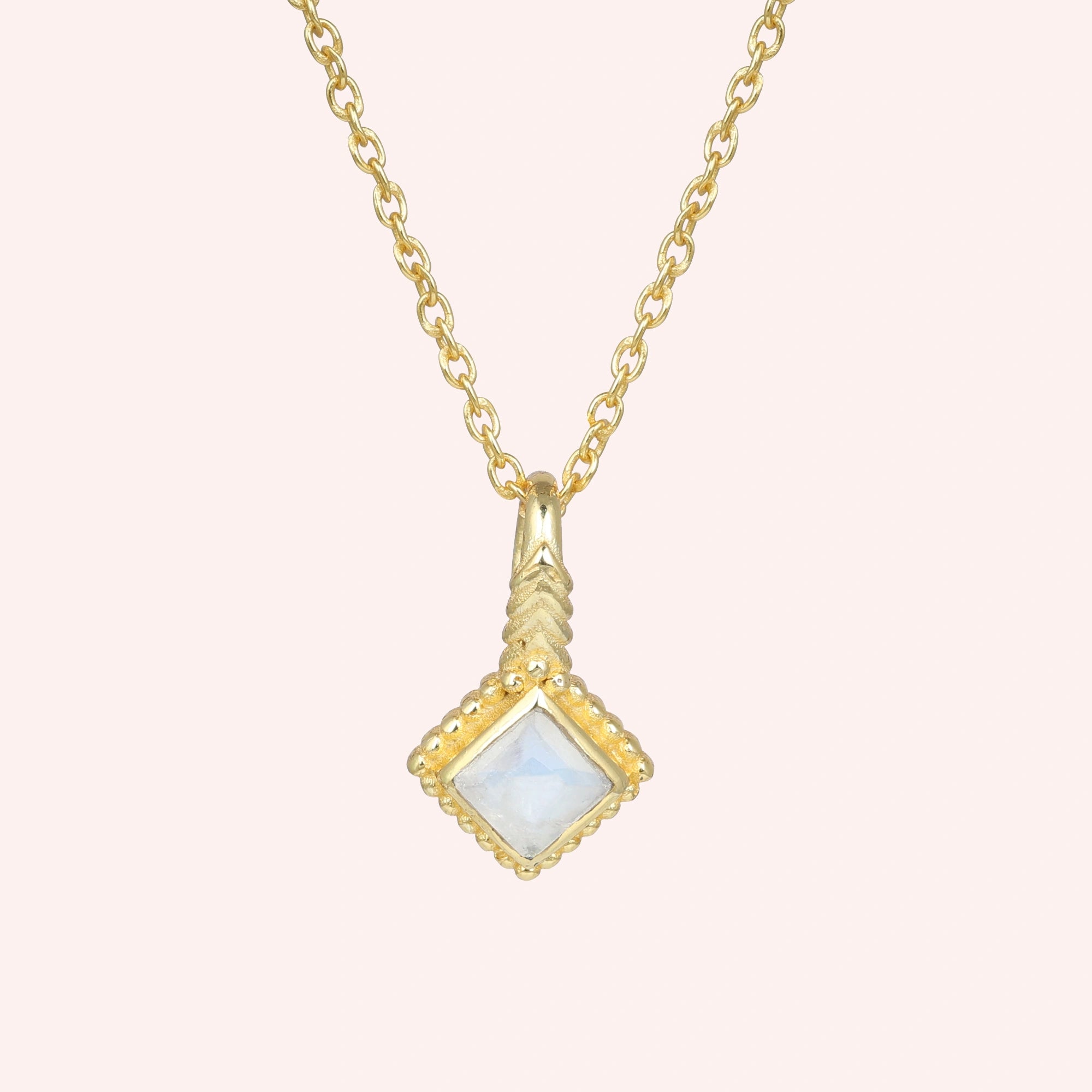 Birthstone_necklace_in_gold_plated_silver_with_square_cut_moonstone_pendant_in_front_angle_view_on_solid_pink_background