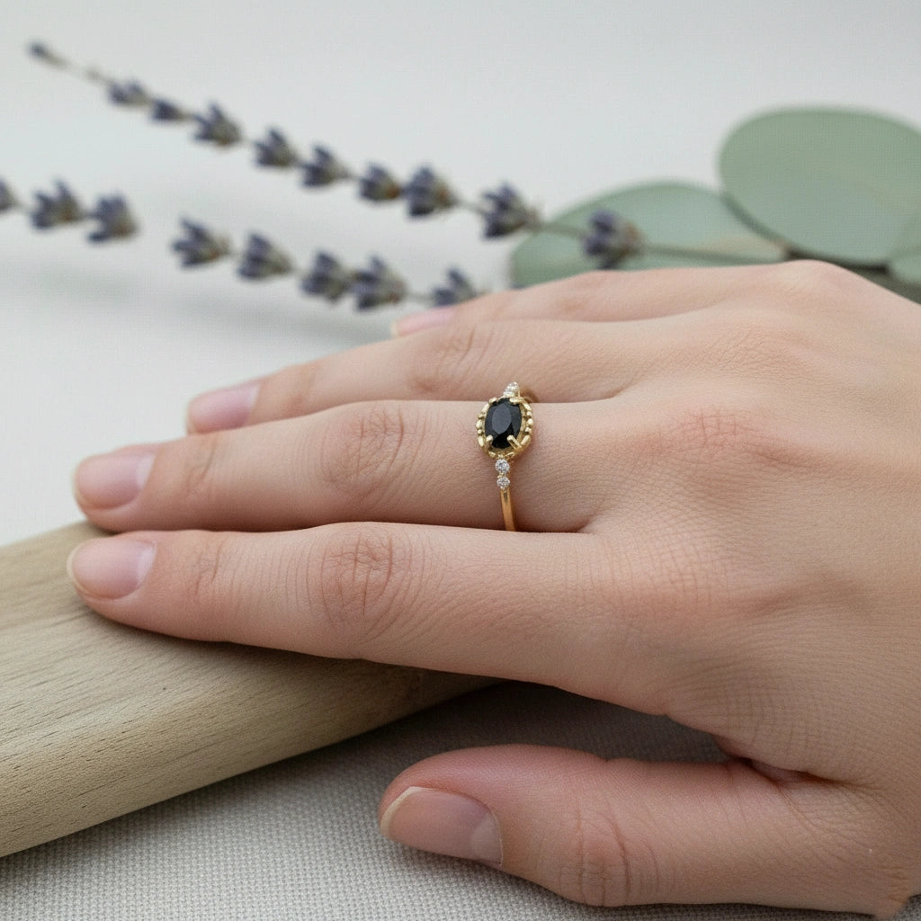 Black-onyx-ring-with-white-topaz-stones-gold-plated-silver-angled-view-on-white-satin-background