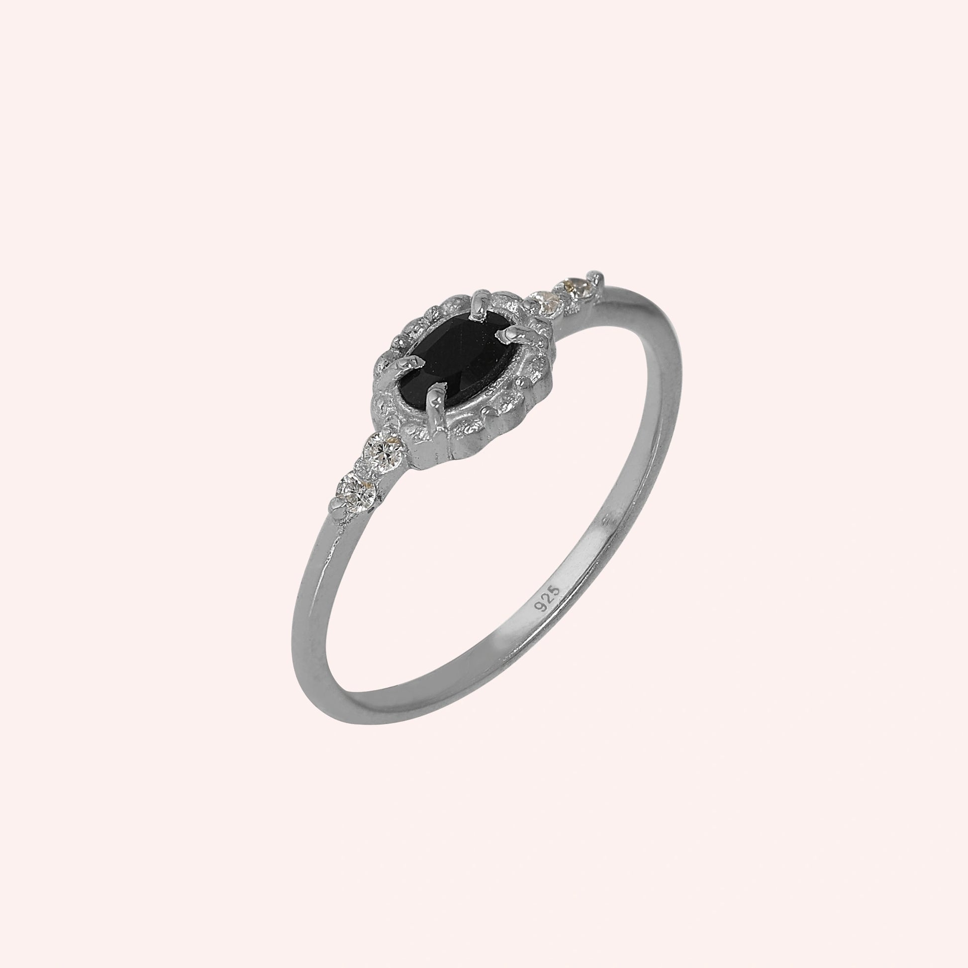 Black-onyx-ring-with-white-topaz-stones-sterling-silver-angled-view-on-soft-pink-background