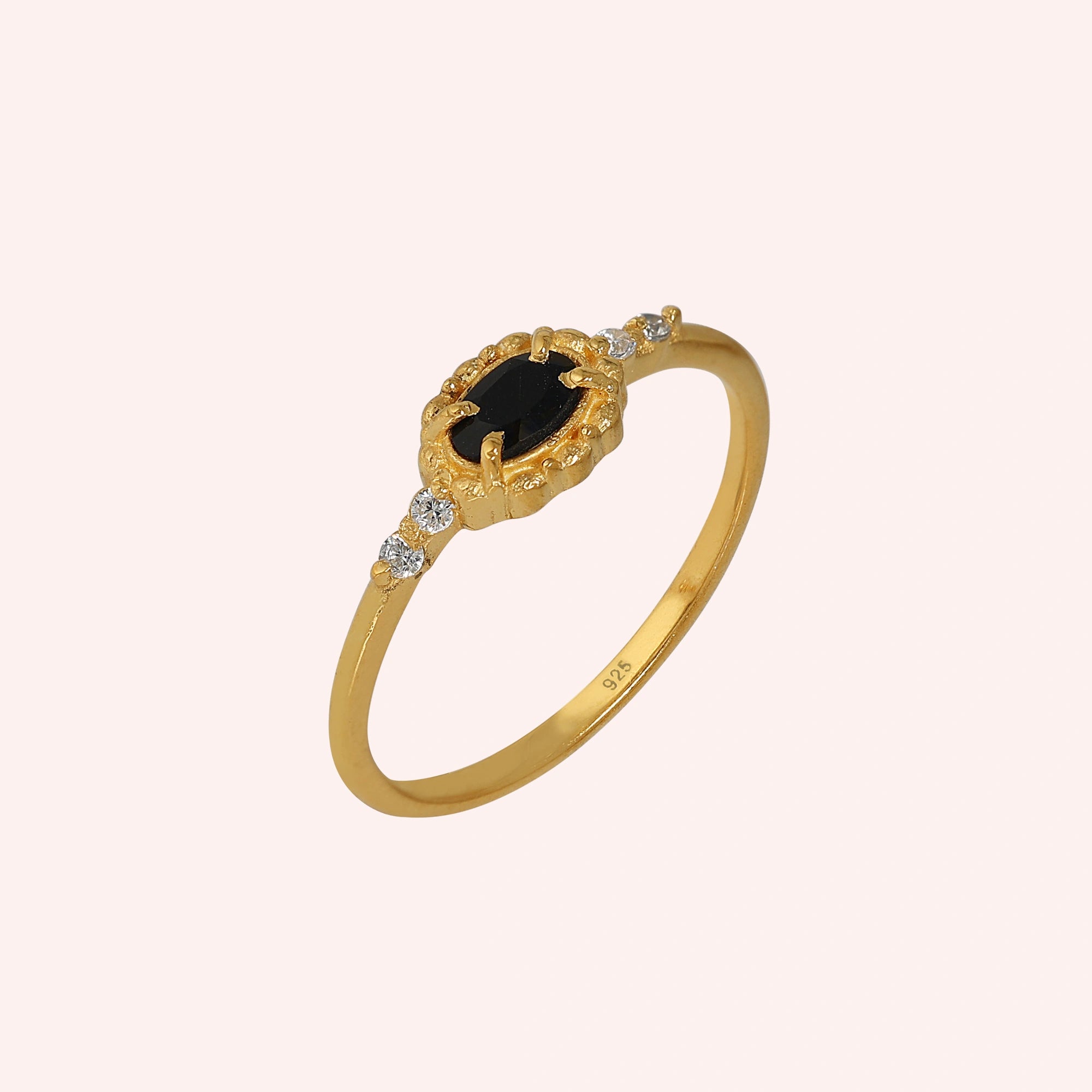 Black-onyx-ring-with-white-topaz-stones-gold-plated-silver-angled-view-on-soft-pink-background