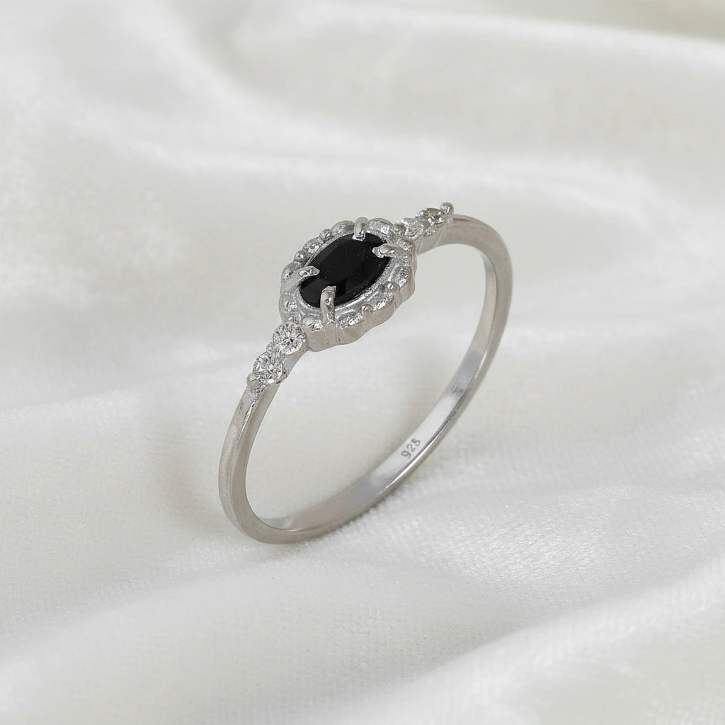 Black-onyx-ring-with-white-topaz-stones-sterling-silver-angled-view-on-white-satin-background