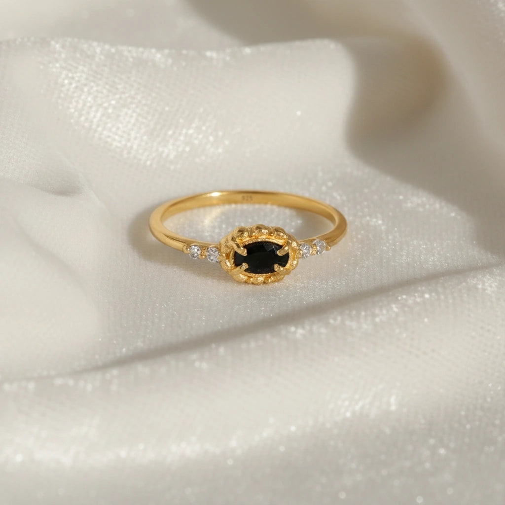 Black-onyx-ring-with-white-topaz-stones-gold-plated-silver-front-view-on-white-satin-background