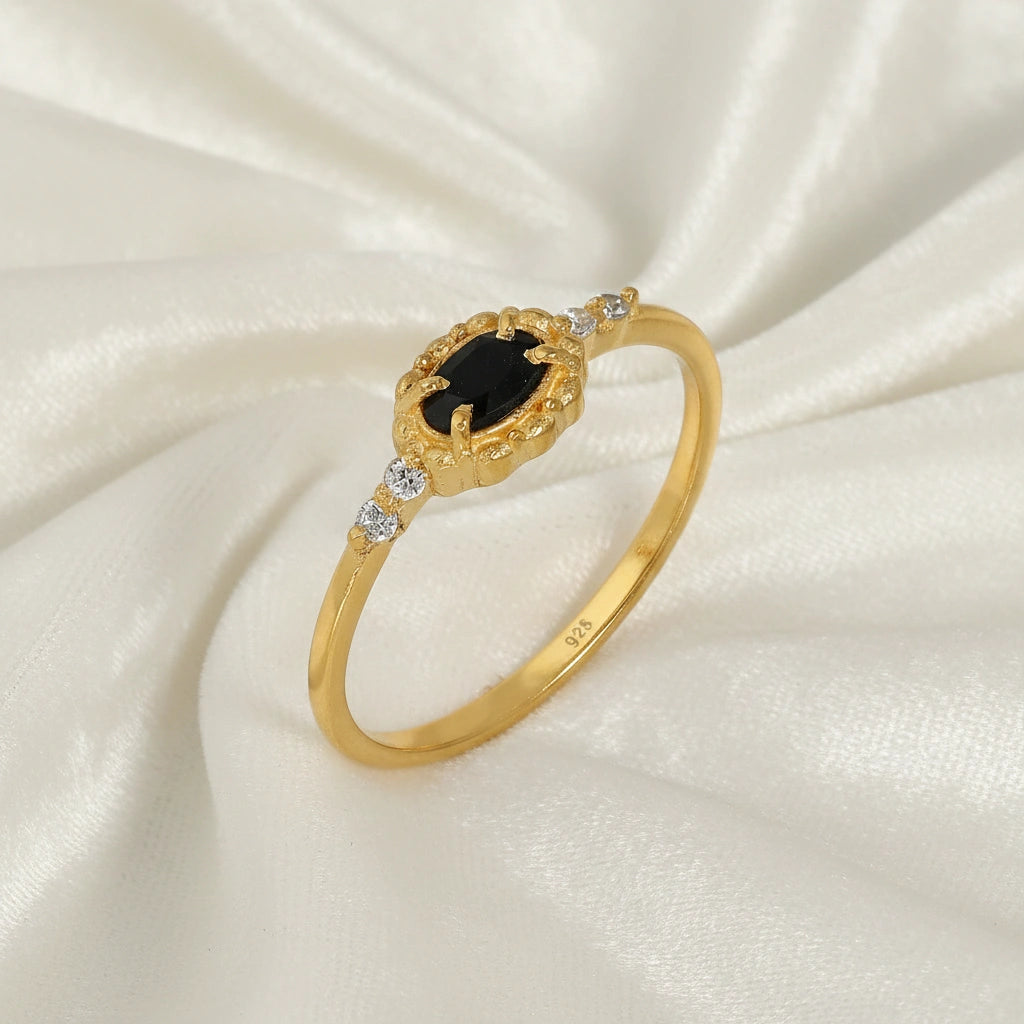 Black-onyx-ring-with-white-topaz-stones-gold-plated-silver-angled-view-on-white-satin-background