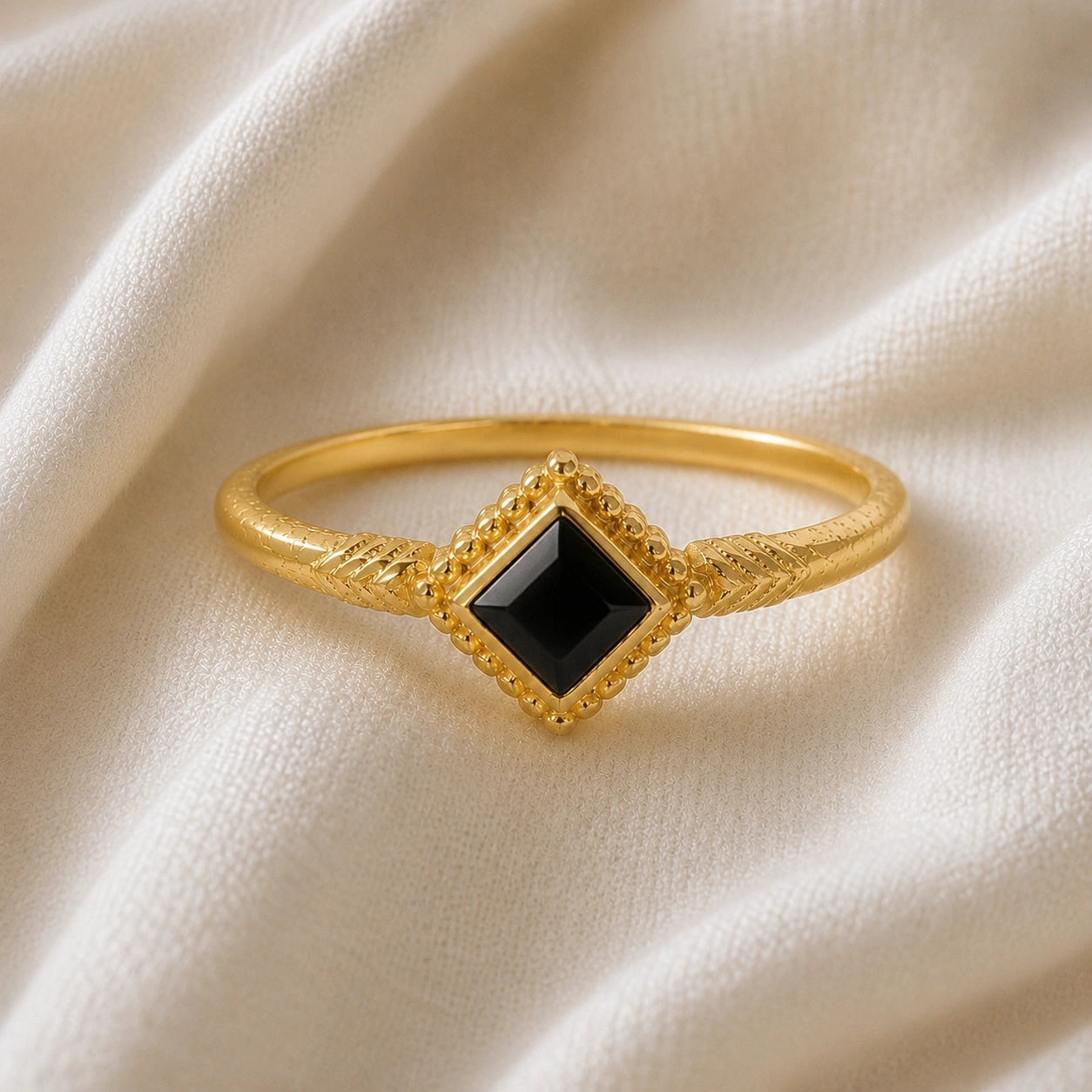 Princess_cut_ring_gold_plated_silver_with_square_black_onyx_and_detailed_band_front_angle_view_on_soft_fabric_background