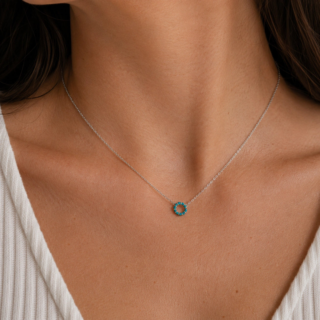 Blue_stone_necklace_in_gold_plated_silver_with_turquoise_stones_in_circle_pendant_at_front_angle_view_on_soft_fabric_background
