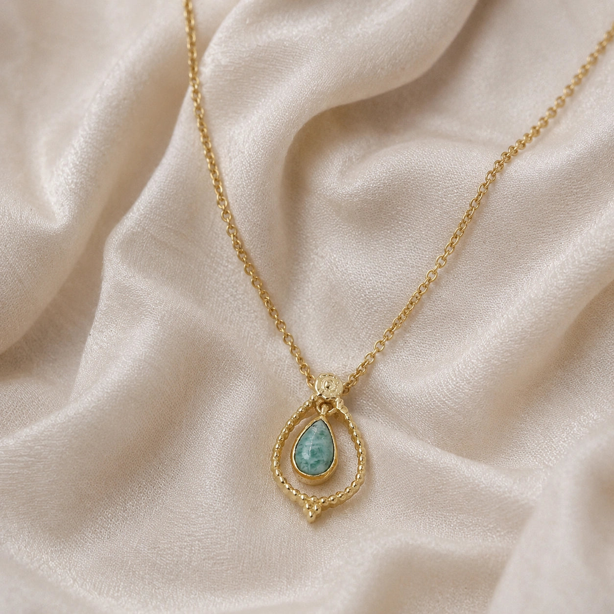 Blue_stone_necklace_in_gold_plated_silver_at_front_angled_featuring_amazonite_stone_on_soft_fabric_background