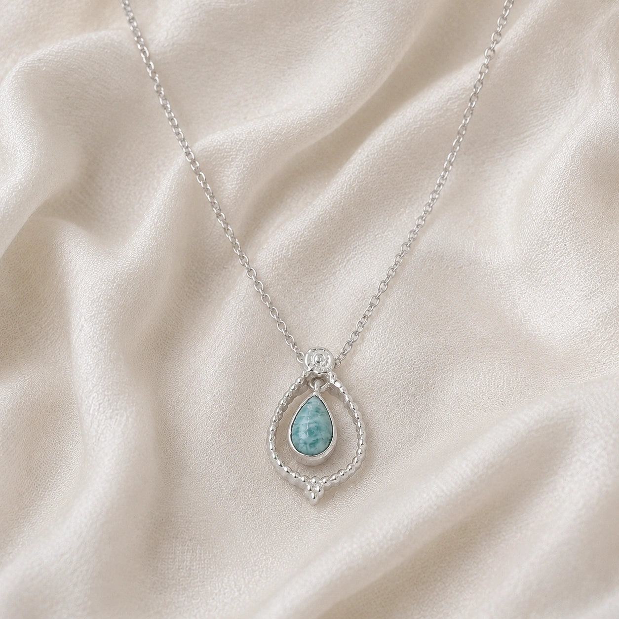 Blue_stone_necklace_in_sterling_silver_at_front_angled_featuring_amazonite_stone_on_soft_fabric_background