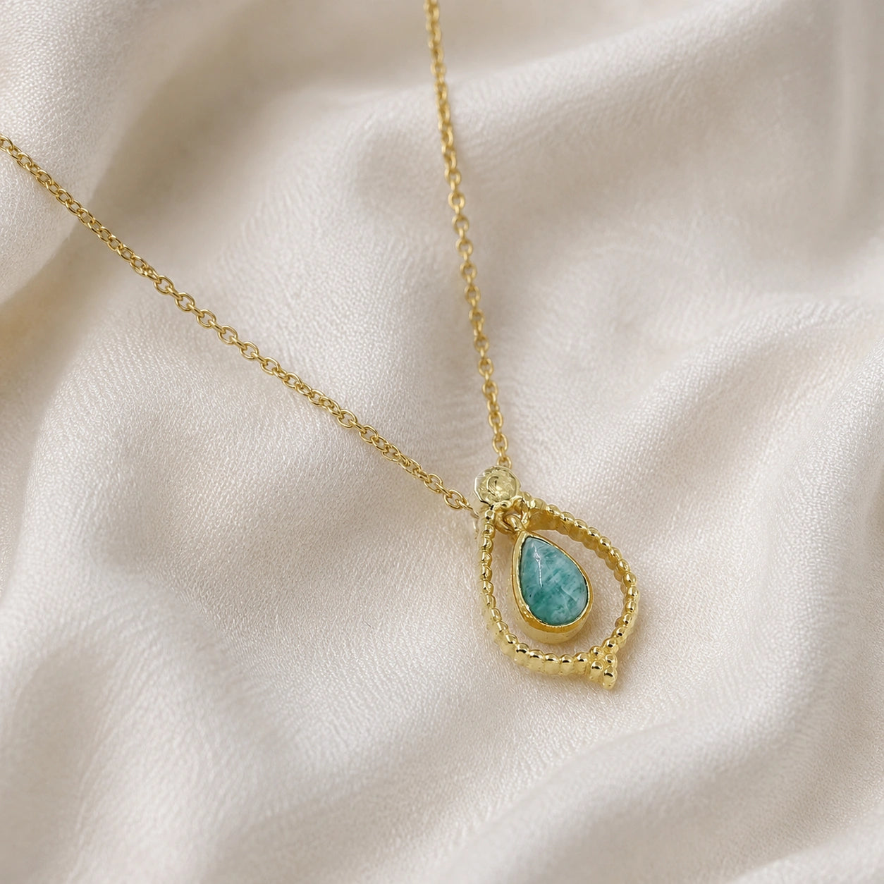 Blue_stone_necklace_in_gold_plated_silver_at_slightly_angled_featuring_amazonite_stone_on_soft_fabric_background