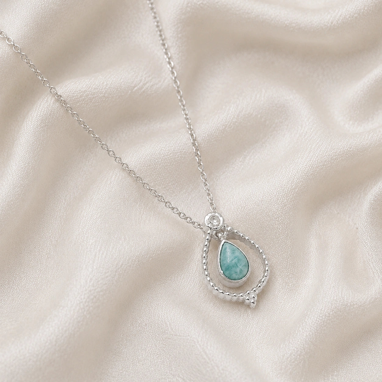 Blue_stone_necklace_in_sterling_silver_at_slightly_angled_featuring_amazonite_stone_on_soft_fabric_background