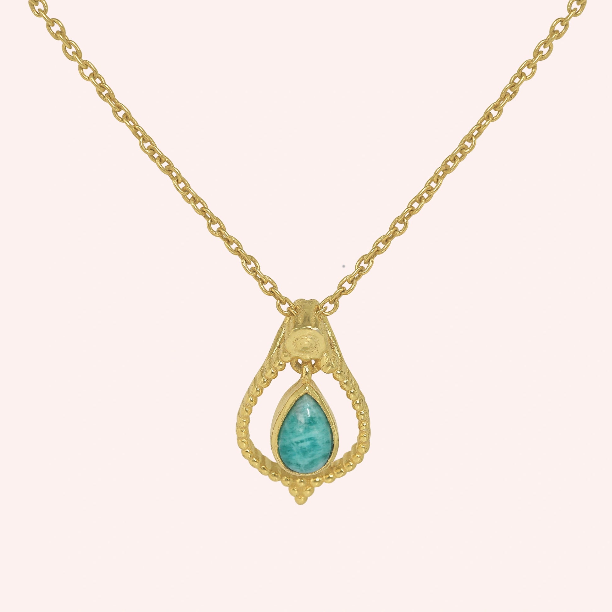 Blue_stone_necklace_in_gold_plated_silver_at_front_angled_featuring_amazonite_stone_on_solid_pink_background