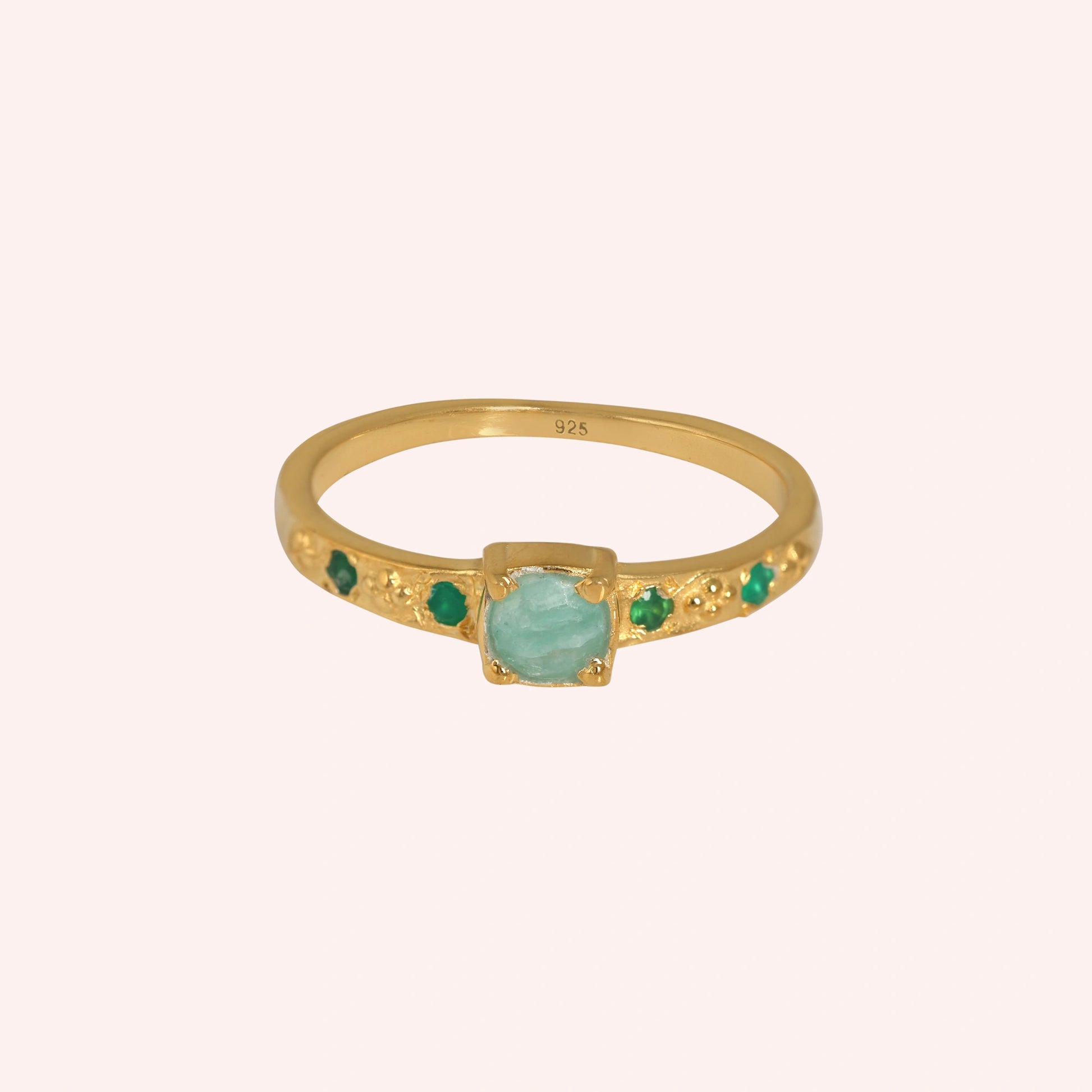 Blue-stone-ring-in-gold-plated-silver-with-green-stones-in-front-view-on-solid-pink-background