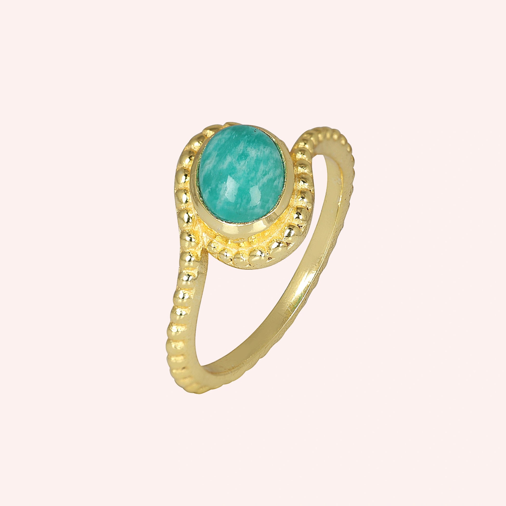 Blue_stone_ring_in_gold_plated_silver_with_an_oval_amazonite_stone_at_slight_angle_view_on_solid_pink_background