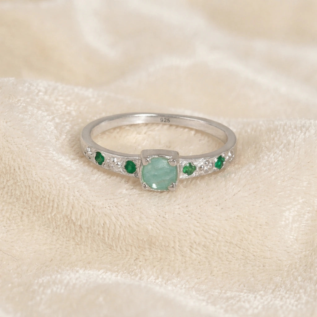 Blue-stone-ring-in-sterling-silver-with-green-stones-in-front-view-on-solid-pink-background