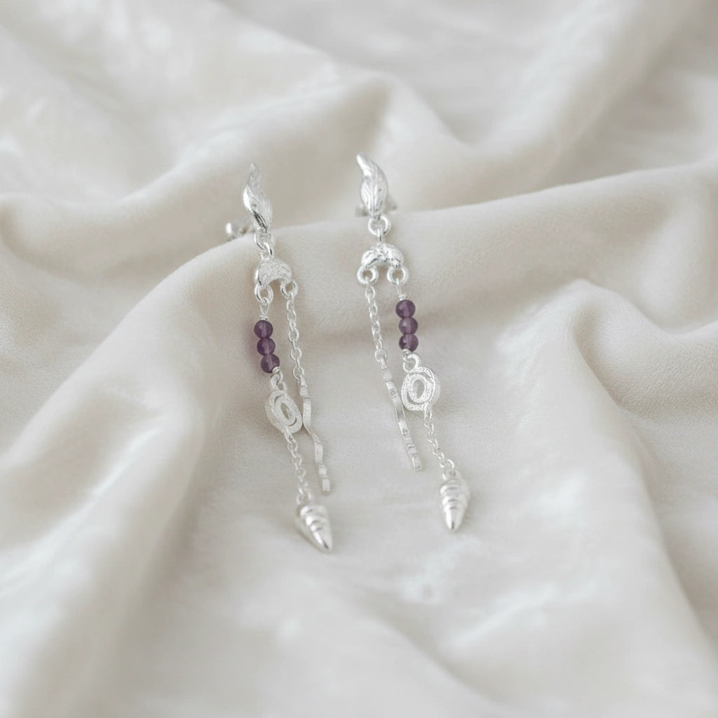 front_angle_boho_silver_earrings_with_purple_beads_and_shell_drops_showing_lightweight_earrings_on_soft_white_fabric_cloth