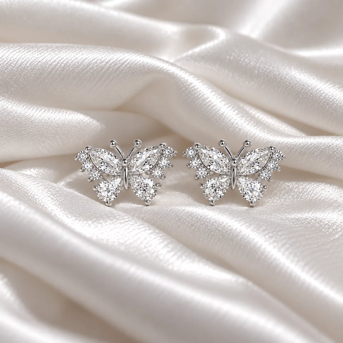 Diamond_butterfly_earrings_in_sterling_silver_with_lab_grown_diamonds_at_front_angle_view_on_soft_fabric_background