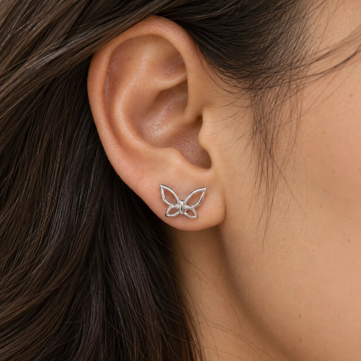 Butterfly_earrings_in_sterling_silver_in_a_stud_design_at_front_angle_view_worn_by_a_model
