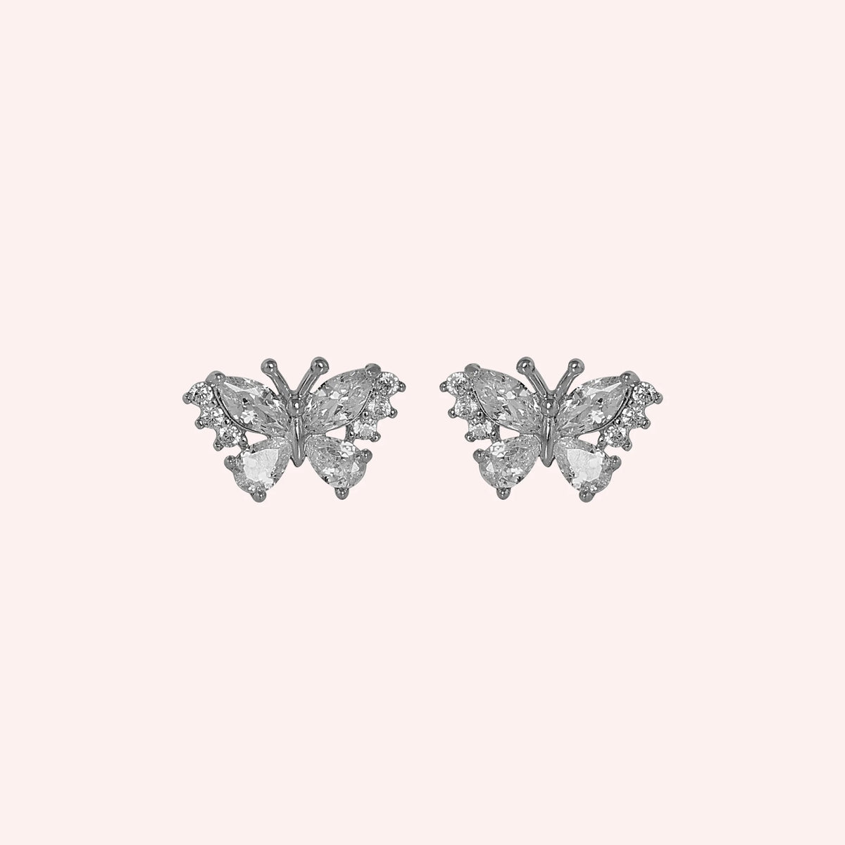 Diamond_butterfly_earrings_in_sterling_silver_with_lab_grown_diamonds_at_front_angle_view_on_solid_pink_background
