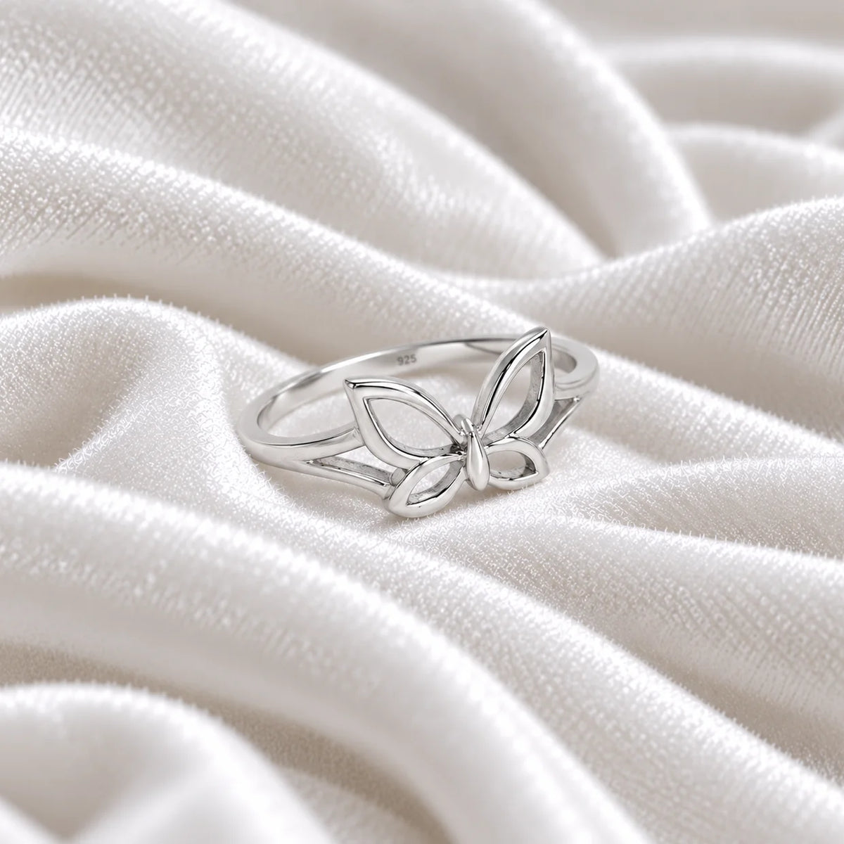 Butterfly_ring_in_sterling_silver_at_side_angle_view_on_soft_fabric_background