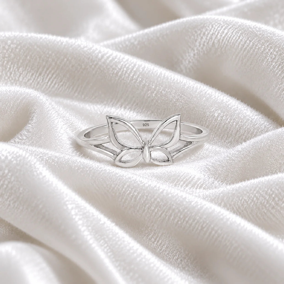 Butterfly_ring_in_sterling_silver_at_front_angle_view_on_soft_fabric_background