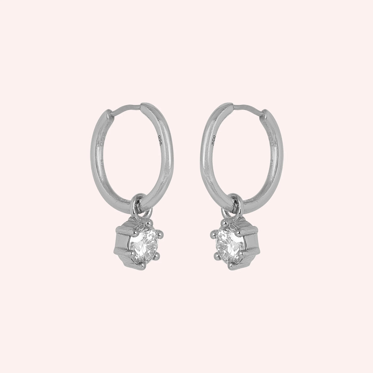 CZ_earrings_in_sterling_silver_with_a_hoop_drop_design_at_side_angle_view_on_solid_pink_background