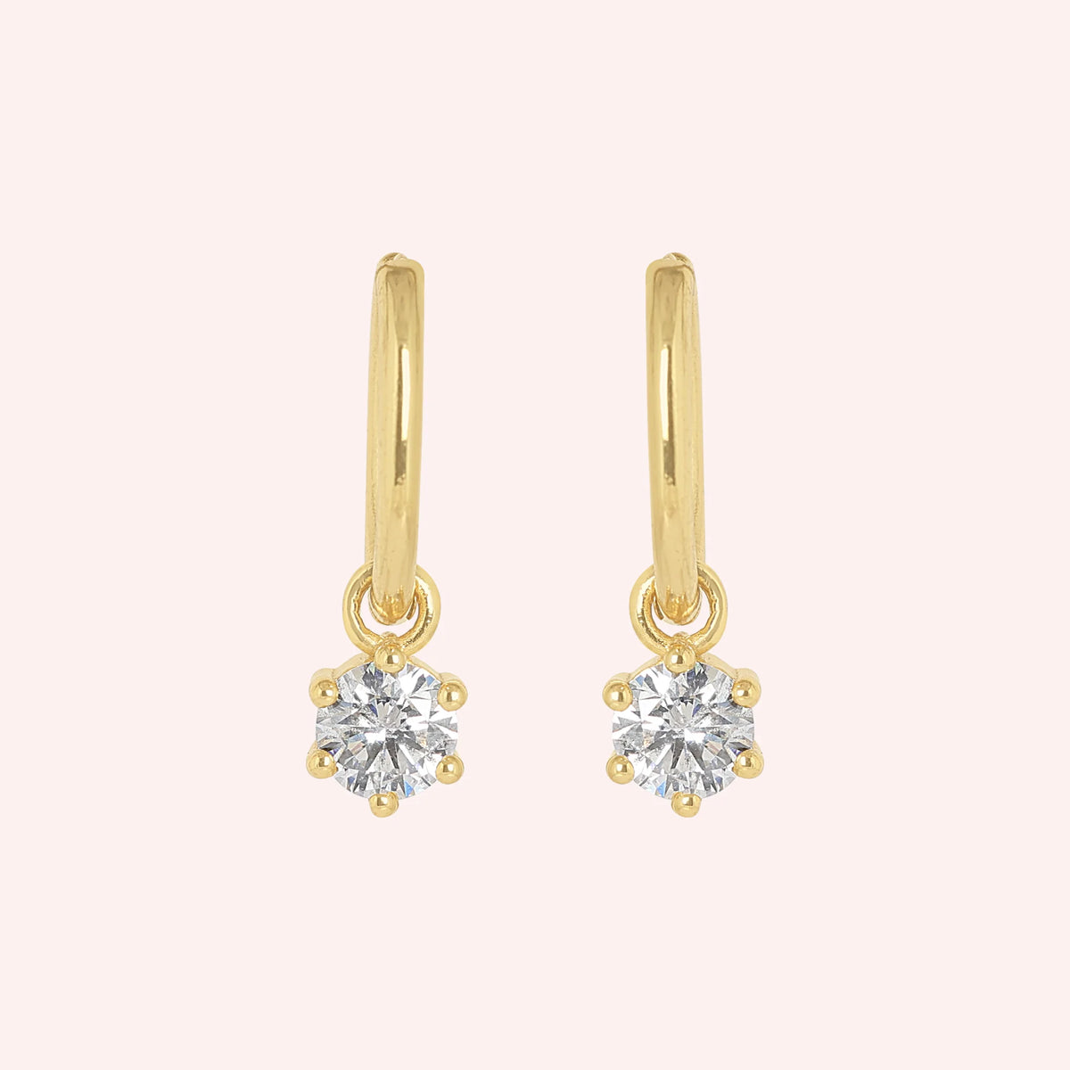 CZ_earrings_in_gold_plated_silver_with_a_hoop_drop_design_at_front_angle_view_on_solid_pink_background