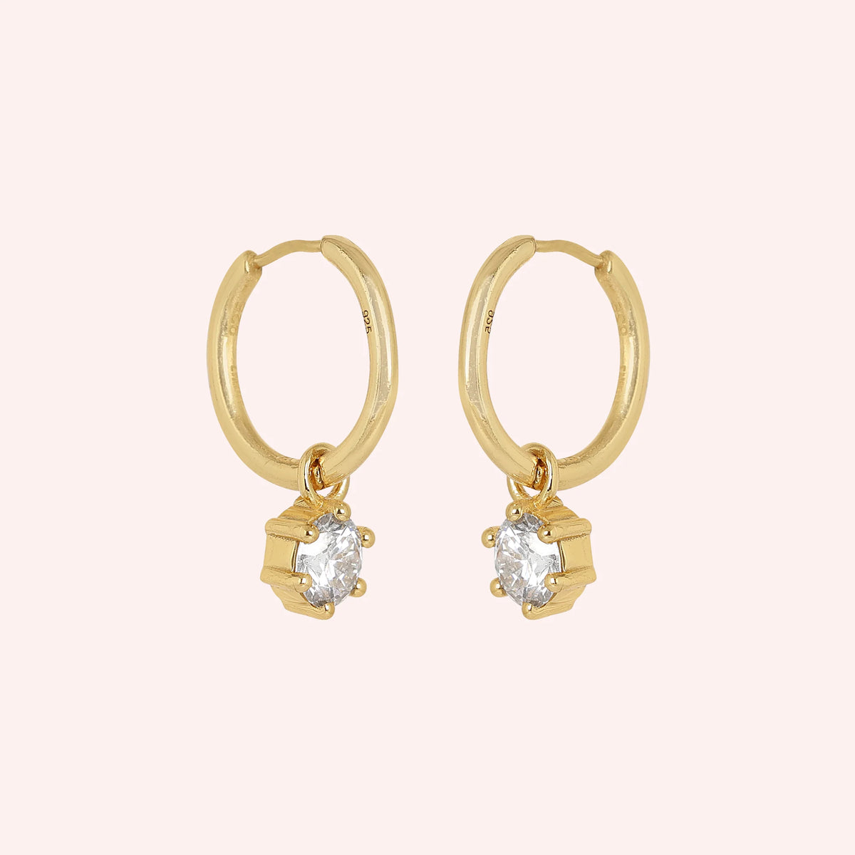 CZ_earrings_in_gold_plated_silver_with_a_hoop_drop_design_at_side_angle_view_on_solid_pink_background