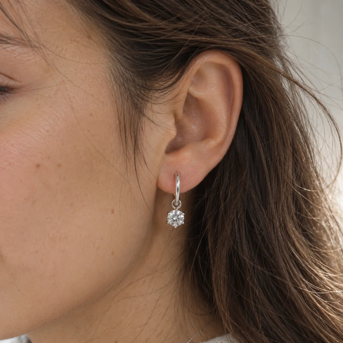 CZ_earrings_in_sterling_silver_with_a_hoop_drop_design_at_front_angle_view_worn_by_a_model