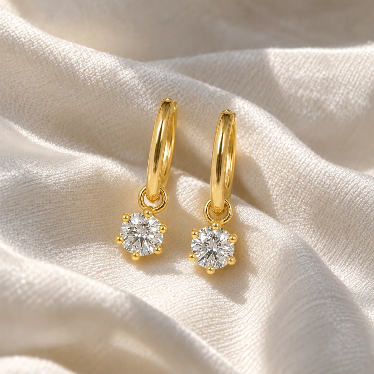 CZ_earrings_in_gold_plated_silver_with_a_hoop_drop_design_at_front_angle_view_on_soft_fabric_background