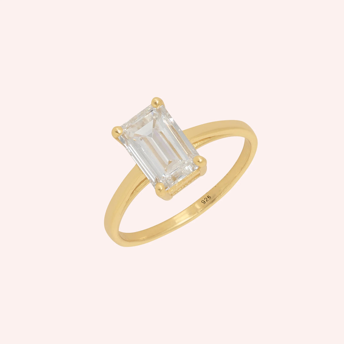 CZ_ring_in_gold_plated_silver_with_a_baguette_shaped_CZ_at_side_view_on_solid_pink_background