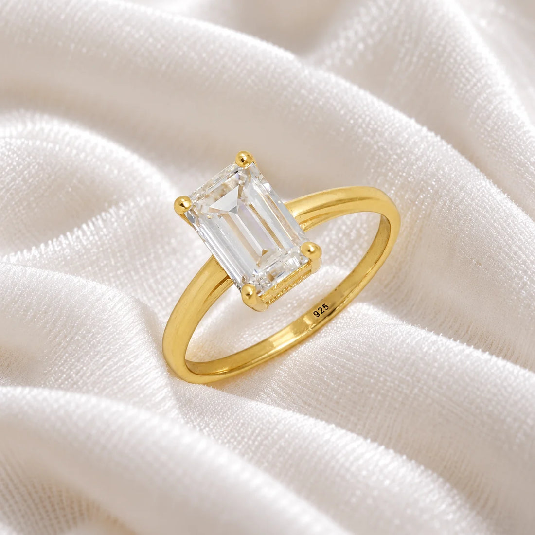CZ_ring_in_gold_plated_silver_with_a_baguette_shaped_CZ_at_side_view_on_soft_fabric_background