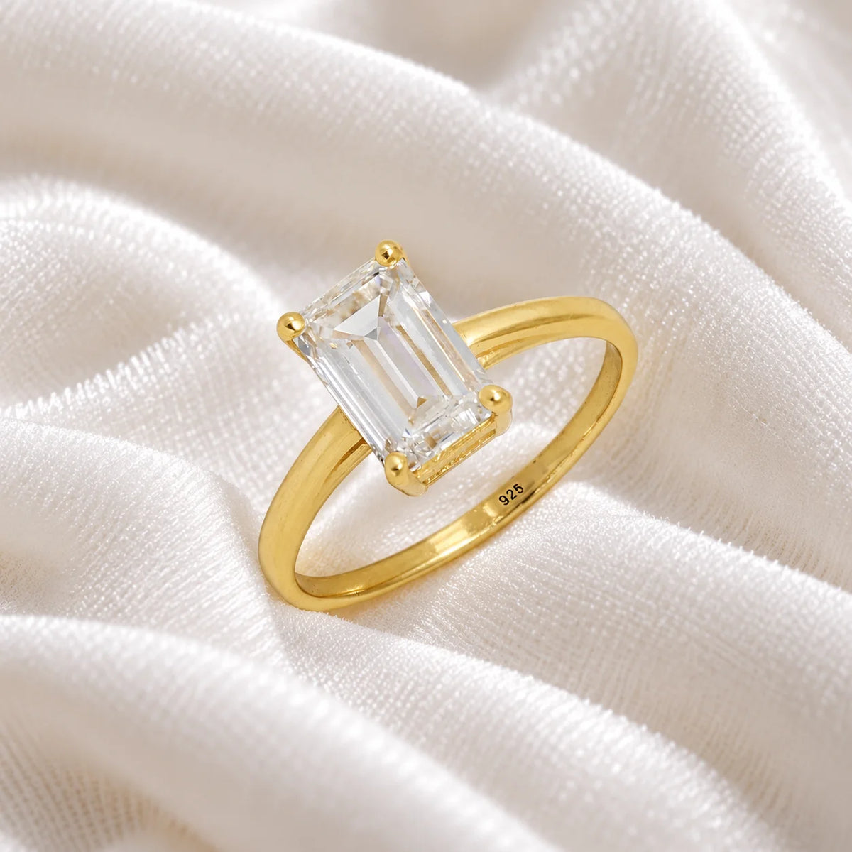 CZ_ring_in_gold_plated_silver_with_a_baguette_shaped_CZ_at_side_view_on_soft_fabric_background