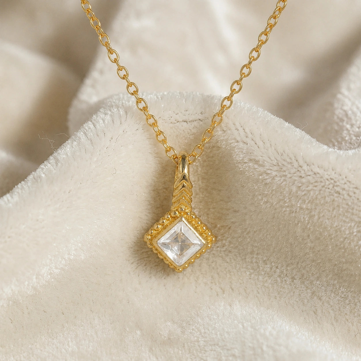 Birthstone_necklace_in_gold_plated_silver_with_square_cut_cz_pendant_in_front_angle_view_on_soft_white_fabric_background